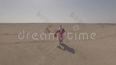 俄<strong>罗</strong>斯圣诞老人或德德<strong>莫罗兹</strong>带着麻袋走在沙子上，在沙漠中找到了沥青路。 日志简介。 空中观景，无人机
