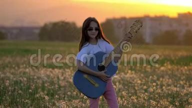 日落时美丽的小女孩在蒲公英地弹吉他。 <strong>远离</strong>城市建筑的户外情感和乐趣