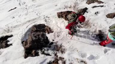 两个穿着全套装备的登山者，带着头盔和背包，克服了厚厚的积雪和滑滑的岩石，爬上了山顶