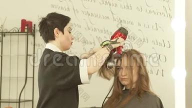 在美发沙龙里用吹风机和梳子给长发发型时，有魅力的女人。 把<strong>剪发</strong>机烘干