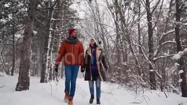 一对相爱的年轻夫妇在下雪的时候在公园里散步。男人和女友手牵手在冬日赏雪
