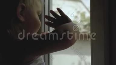 母亲站在一扇窗前，一个小孩子站在一个剪影里
