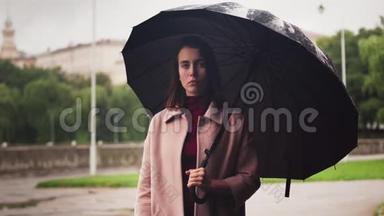 雨中站在<strong>伞下</strong>的年轻严肃的女人，城市的悲伤天气