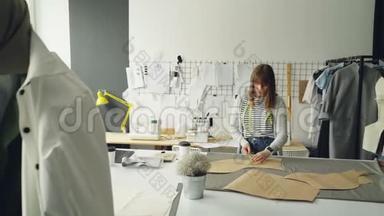 年轻迷人的女设计师正在用测量带检查她的纸模板。 专业创意服装