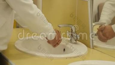 在公共卫生间用白色衬衣洗手的特写男士