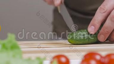 人在砧板上割一根青黄瓜.. 桌子上有蔬菜