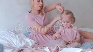 年轻迷人的金发母亲把头发扎成辫子，她的小女儿穿着粉红色的裙子，而她在玩