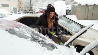 4k视频美丽微笑的年轻女子用伸缩刷子从雪中清洁汽车