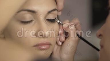 化妆师将化妆霜涂于女孩的眼部区域