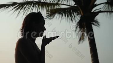 在日落时分，年轻的旅游妇女使用手机、智能手机、音频信息、语音识别应用程序ai