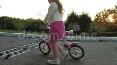 一个快乐、美丽、金发碧眼<strong>的</strong>小女孩穿着粉红色<strong>的裙子</strong>，跳投骑着一辆<strong>儿童</strong>`自行车上路