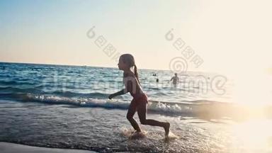 一个赤脚的小女孩在晚阳的温暖光线下沿着大海在潮湿的沙子上奔跑的缓慢运动。 粗心和粗心