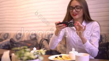 美丽的年轻女子在<strong>咖</strong>啡馆里用手机相机为社交<strong>网</strong>络拍照她的食物和<strong>咖</strong>啡。 4千克