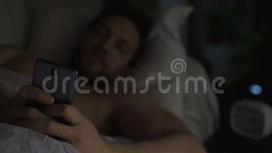 失眠的人睡不着，在床上在智能手机上滚动，失眠