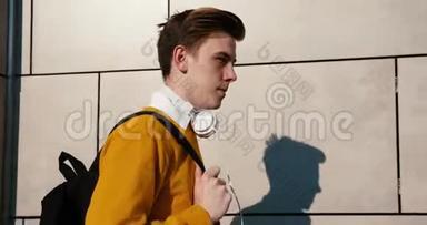 穿着黄色毛衣的迷人少年的侧面肖像沿着街道走着。 他拿着<strong>袋子</strong>