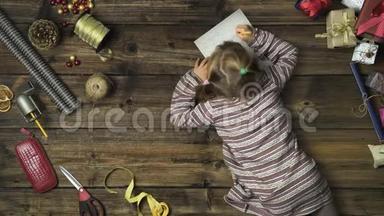 头顶上的女孩在老式木桌上写圣诞老人的信，而妈妈则在用<strong>手工艺</strong>品准备礼品盒