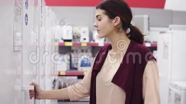 20`的小女孩走到电器商店的<strong>冰箱</strong>前，打<strong>开门</strong>，检查里面`什么。 她打开了