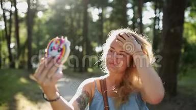 穿着漂亮的欧洲女人在日落时分在森林里用手机自拍和发短信，在户外自拍