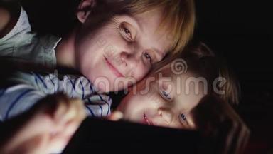 快乐的母亲和她的女儿。 我一起玩平板<strong>电脑</strong>，<strong>面对</strong>面躺在床上