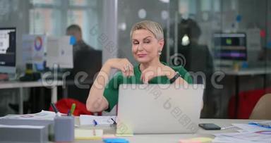 白种人成熟的女人坐在笔记本电脑前跳舞