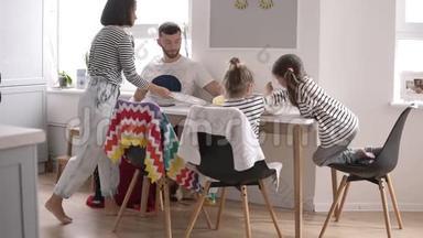 幸福的年轻<strong>一家人</strong>和小孩子一起在家里的白色厨房里<strong>吃早餐</strong>。 吃煎饼