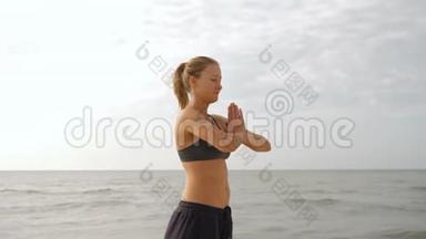 年轻女子在海滩上放松和日光浴。 美丽的女人在做瑜伽，站在沙滩上摆出海景