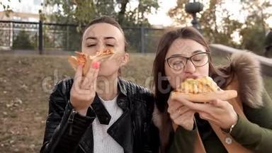 两个女孩坐在公园里，吃着美味的大<strong>披萨</strong>，里面有<strong>鸡肉</strong>和蘑菇