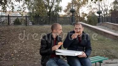 两个人坐在公园里吃披萨和鸡肉聊天