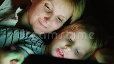 快乐的母亲和她的女儿。 我一起玩平板<strong>电脑</strong>，<strong>面对</strong>面躺在床上