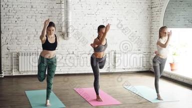三位年轻女士在现代<strong>健康</strong>中心<strong>练</strong>习瑜伽时，正在<strong>练</strong>习舞王的姿势