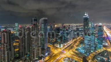 迪拜商务海湾塔楼在夜间时间推移时照明。 从屋顶可以看到一些摩天大楼和下面的新塔楼