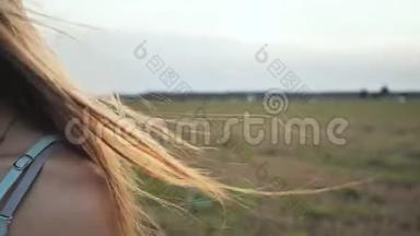 棕色头发的年轻女孩的长发在傍晚的阳光下随风<strong>飘散</strong>。