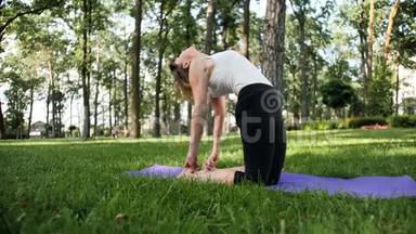 美丽<strong>微笑</strong>的中年妇女在公园里<strong>做瑜伽</strong>练习和伸展运动的4K慢动作视频。 它是非常