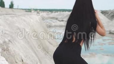 穿着黑色运动服的运动型黑发女孩在一个蓝水白垩沙场上训练。 执行<strong>下蹲</strong>任务