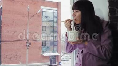 女商人坐在窗台上吃方便面，靠在砖楼上