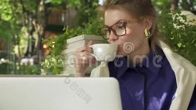 戴眼镜的嬉皮士女孩在笔记本电脑附近的<strong>夏日咖啡</strong>馆喝<strong>咖啡</strong>