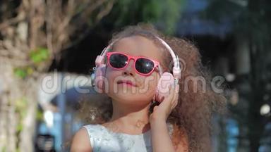 一个可爱的孩子的肖像，一个穿着粉色眼镜和粉色耳机的白色裙子的美丽的小女孩