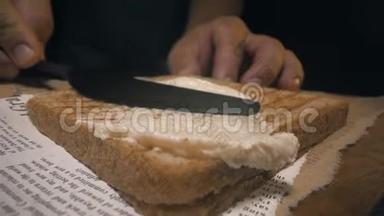 特写镜头：厨师用刀把黄油涂在脆烤面包上，做三明治，自制快餐