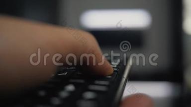 一个手里拿着<strong>遥控器</strong>的人看电视，按下<strong>遥控器</strong>上的按钮。