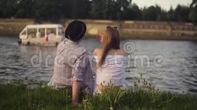 特拉迪夫妇在河边聊天。 假期，假期，爱和人的概念-快乐的青少年夫妇坐在维斯拉河边