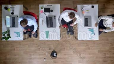 三个年轻的商人在工作场所玩扔纸游戏，休息观念，办公室观念，沟通观念，顶级射击