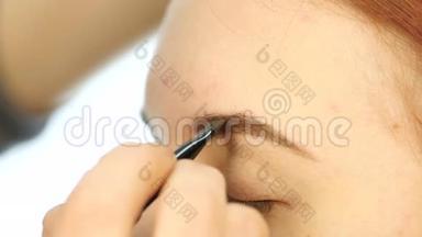 特写化妆师`他的手用刷子为一个漂亮的客户画眉毛。 慢动作