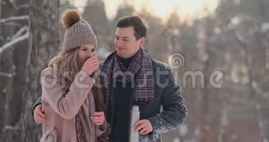 一对相爱的夫妇在冬天的森林里<strong>喝热水</strong>瓶里的茶。 穿外套的时髦男女