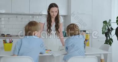 妈妈在厨房洗碗，两个儿子坐在办公桌前，用彩色<strong>铅笔</strong>在纸上<strong>画画</strong>。