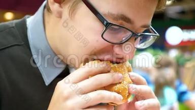 一个年轻人正在购物中心吃汉堡包。