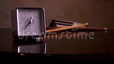 在一张光滑的棕色木桌上，有一个反光，有一个白色表盘、一个钟和鼓棒的方形银