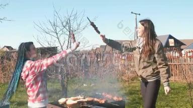 两个女朋友在后院的木炭烤架上做什什利克肉。 一起<strong>说说</strong>笑笑，休息一下