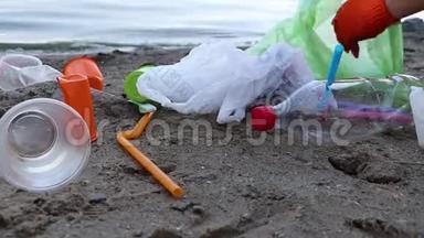 海滩上的垃圾收集。 塑料和包裹散落在海滩上。 一个人收集塑料。 生态保护概念