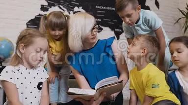 孩子们坐在枕头上，老师在小学或小学的课堂上给他们读有趣的书