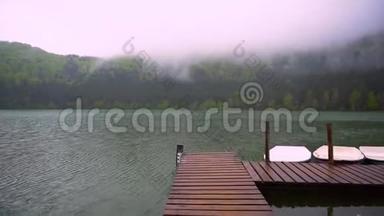 小船漂浮在靠近<strong>木墩</strong>的湖面上。 平静的山湖表面。 雾蒙蒙的山林